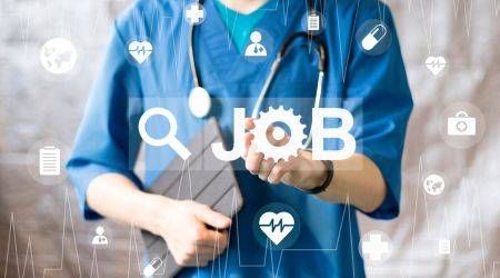 MaximP/shutterstock.com Eine junge Medizinerin hält ein Tablet im Arm und zeigt auf den Begriff "Job", welchem eine Lupe vorangestellt ist